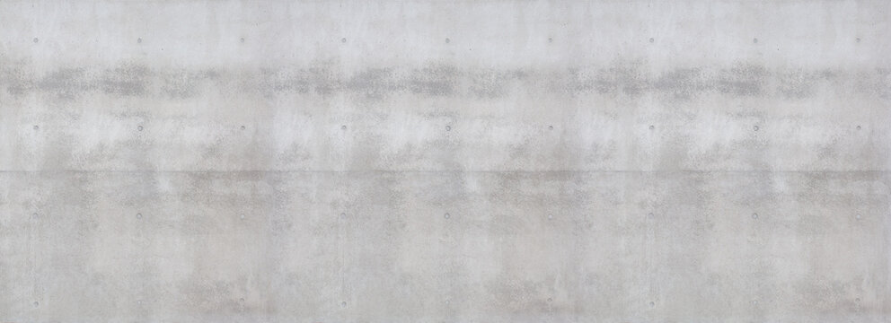 A concrete surface with a distinctly rough, irregular texture. The structure shows porous inclusions, fine cracks, formwork board marks, and irregular shadows due to the grainy surface.