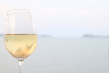 glass of cold white wine on the summer seashore by the water, relaxing by the water, a gentle background of soft color