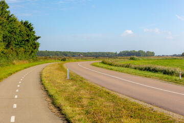 Fototapeta premium Countryside road between Den Brug and Den Hoorn with curve and green grass, Typical Dutch polder land, Texel is one of the Dutch Wadden Islands off the coast of the Netherlands, Noord Holland province