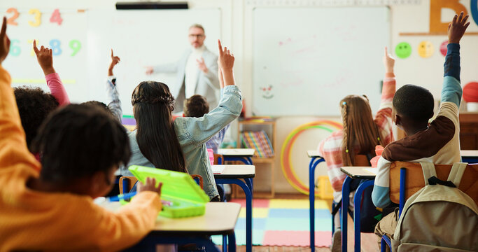 Teacher, students and arms raised in classroom with kids for education, question or answer for knowledge. Man, children with why or learning for academic growth, future and educator teaching in class - Powered by Adobe