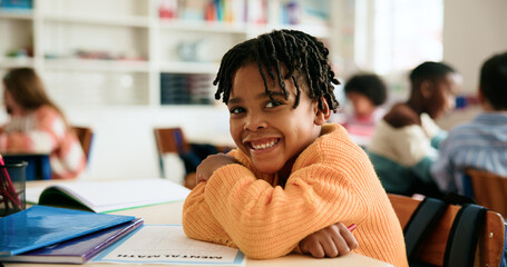 Boy, arms crossed and portrait in classroom with education, smile and confidence for learning at academy. Kid, happy learner and pupil with paper, math or development with pride at elementary school