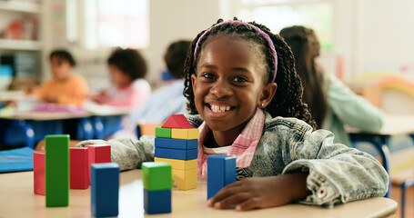 Building blocks, portrait and smile of student girl at desk in classroom of elementary school....