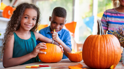 Fototapeta premium Kids carving pumpkins together for Halloween fun activity