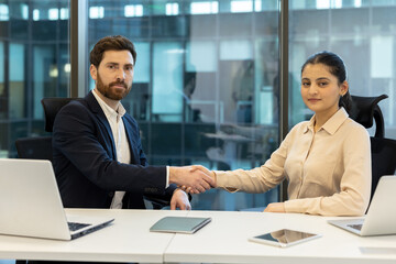Businesspeople shaking hands after successful meeting in office