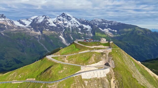 Aerial view of the winding Grossglockner High Alpine Road cutting through lush green mountains towards snow-capped peaks, a scenic route, Bruck an der Gro&szlig;glocknerstra&szlig;e, Salzburg, Austria.