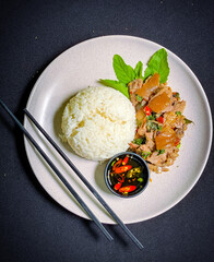 Stir-fried  pork leg with holy basil served over rice, a popular Thai street food dish full of spicy and aromatic flavors.