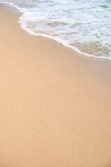 Closeup of waves sand beach and blue summer sea.