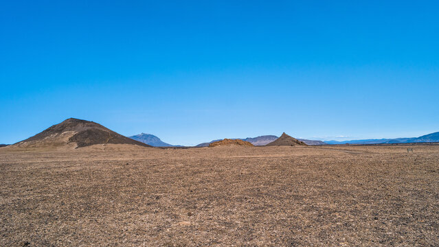 Panoramic view at Askja caldera hiking trail in the lifeless volcanic desert in Highlands, with stones and rocks thrown by volcanic eruptions, Iceland, summer, blue sky.
