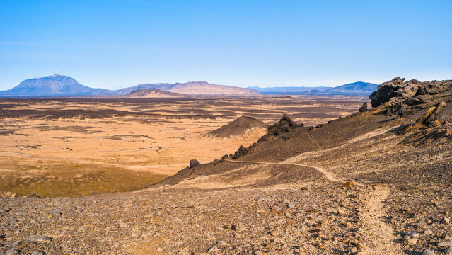 Panoramic view at Askja caldera hiking trail in the lifeless volcanic desert in Highlands, with stones and rocks thrown by volcanic eruptions, Iceland, summer, blue sky.