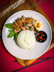 Stir-fried  pork leg with holy basil served over rice, a popular Thai street food dish full of spicy and aromatic flavors.