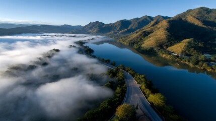 Misty river scene with a winding road, mountains, and clear blue sky