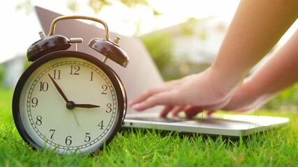 Working on a laptop in a green park with a clock in the foreground reflects time management, work-life balance, flexible schedules, productivity outdoors, and mindful use of technology.
 - Powered by Adobe