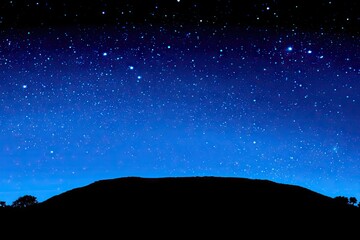 Dark silhouette mountain against a vibrant night sky filled with stars