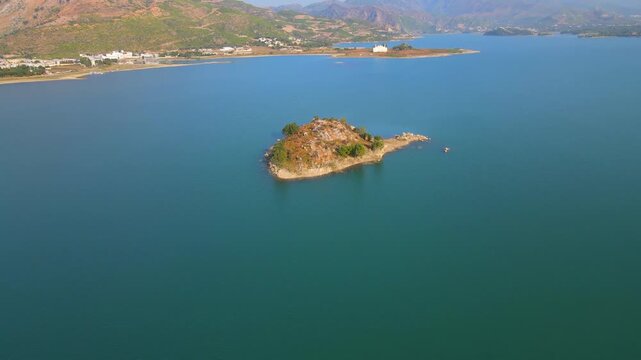 Aerial view of an island with sparse vegetation surrounded by the still, turquoise waters of Khanpur Lake, Khanpur, Khyber Pakhtunkhwa, Pakistan.