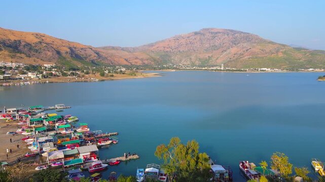 Aerial view of colorful boats docked at Khanpur Lake, reflecting the clear blue sky, surrounded by mountains and lush greenery, Khanpur, Khyber Pakhtunkhwa, Pakistan.
