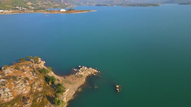 Aerial view of the calm, turquoise waters of Khanpur Lake contrasting with the rugged, rocky terrain of small islands, Khanpur, Khyber Pakhtunkhwa, Pakistan.