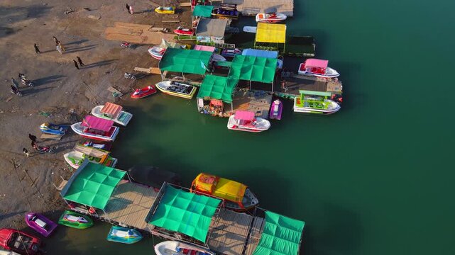 Aerial view of colorful boats docked along the shores of Khanpur Lake where people are enjoying the scenic views, Khanpur, Khyber Pakhtunkhwa, Pakistan.