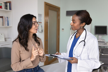 African doctor attentively listening complaints of elderly woman patient