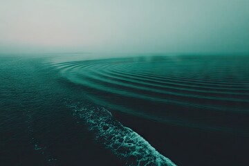Misty teal water, ripples, and wake
