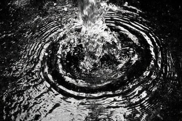 Water splashes down, creating concentric ripples in dark water