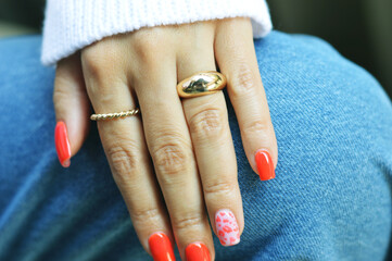 Female hand with bright red summer manicure on denim background.
