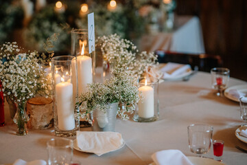 Close-up of a wedding table centerpiece with lit candles, baby’s breath flowers, and elegant table settings, creating a warm and romantic atmosphere.