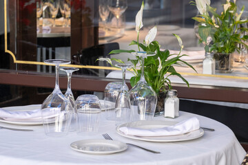 Elegant restaurant table for two with a white tablecloth and fine wine glassware, white crockery.