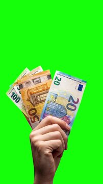 Hand holding up Euro banknotes on green background