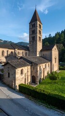 A picturesque view of a medieval stone church with a tall, ornate tower, nestled amidst rolling hills and lush greenery.