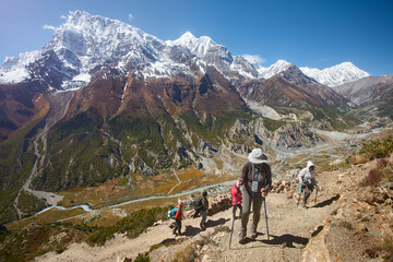 Group of tourists climbs trail up mountain to Ice Lake, during Annapurna Circuit trek in Himalayas. Nepal