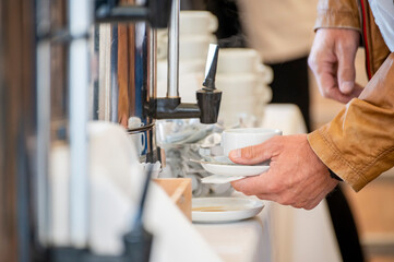 man pouring coffee from dispenser at breakfust buffet