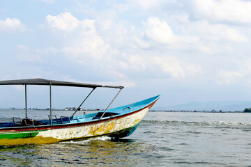 Fototapeta premium Traditional Wooden Boat Floating on Lake with Scenic Sky