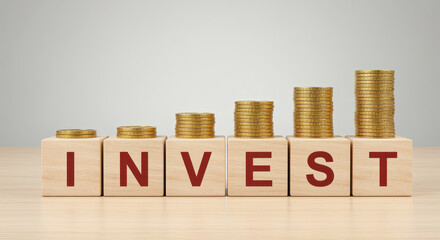 Wooden Blocks Spelling " INVEST" with Stacks of Coins on Top invest investment