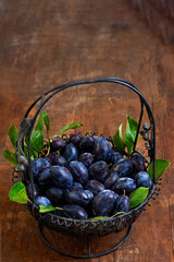 Fresh plums in a rustic basket on a wooden table
