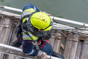 A deckhand prepares the pilot ladder as the ship readies for port entry. Secured in a safety...