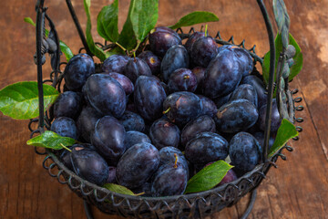 Fresh plums in a rustic basket on a wooden table