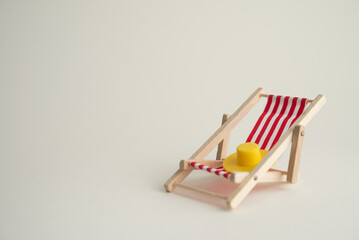 Red beach chair and sun hat on white background copy space. Summer beach holiday, creative design, annual leave travel period of paid time off (PTO) for relaxation and so on concept.