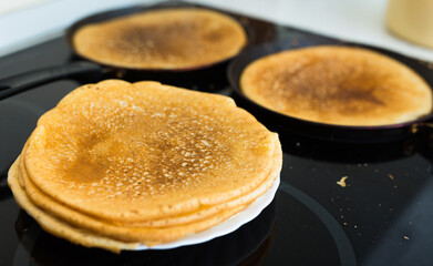 freshly baked hot cereal pancakes on plate and pans during cooking