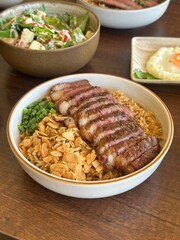 Perfectly Medium-Rare Grilled Beef Slices Served over Rich Beef Fat Fried Rice, a Hearty and Savory Asian-Style Dish with Crispy Garlic.