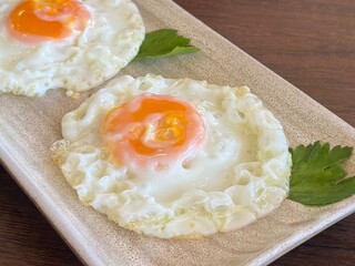 Side view of two Fried Eggs on a Wooden Plate