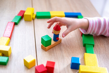 Child fun playing with wooden toys, play time, Colorful blocks and figures on table. Early education, fine motor skills concept