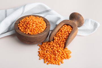 Red lentils in wooden bowl and spoon. Healthy Gluten-Free legume rich in protein, fiber, vitamins and minerals.