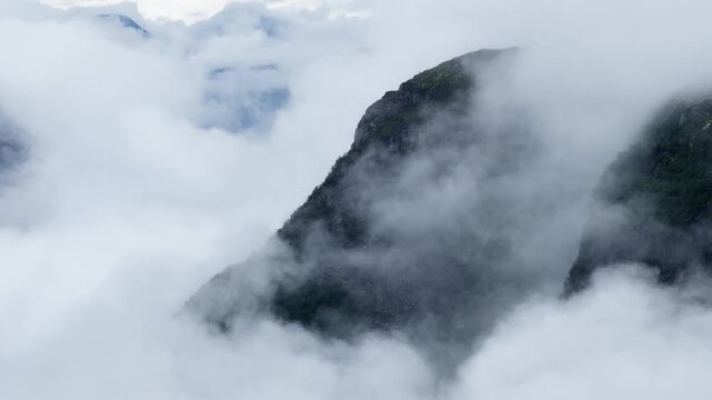 Aerial footage of the dense fog wraps the mountains near Oldevatnet lake, Norway on a cloudy day