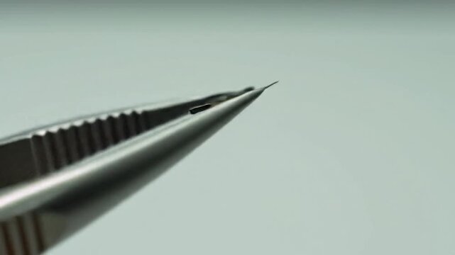 Close-up of tweezers precisely holding and manipulating a tiny mechanical component for assembly or inspection.