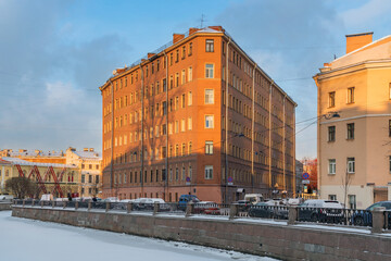 Obraz premium View of a residential building in the shape of an iron on the embankment of the Griboyedov Canal on a sunny winter day, St. Petersburg, Russia