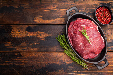 Ready for cooking beef cheeks, raw meat in skillet. wooden background. top view