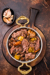 Slow cooked Beef Cheek, Braised meat with vegetables in a skillet. brown background. top view