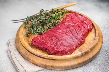 Flank steak, raw beef meat with herbs for frying. grey background. top view