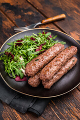 Roasted beef and lamb meat kebabs sausages  on plate with salad. wooden background. top view