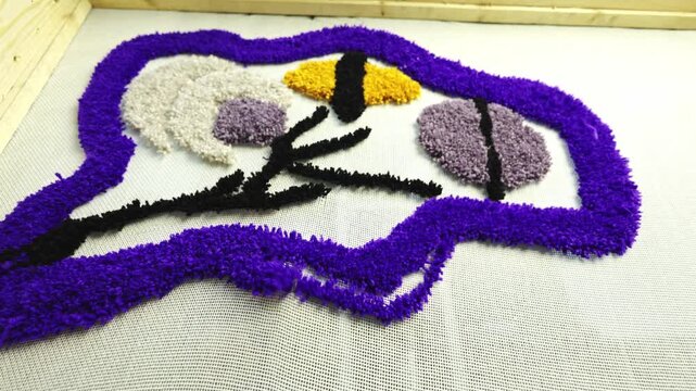 Needle of tufting gun weaving colorful carpet on canvas 